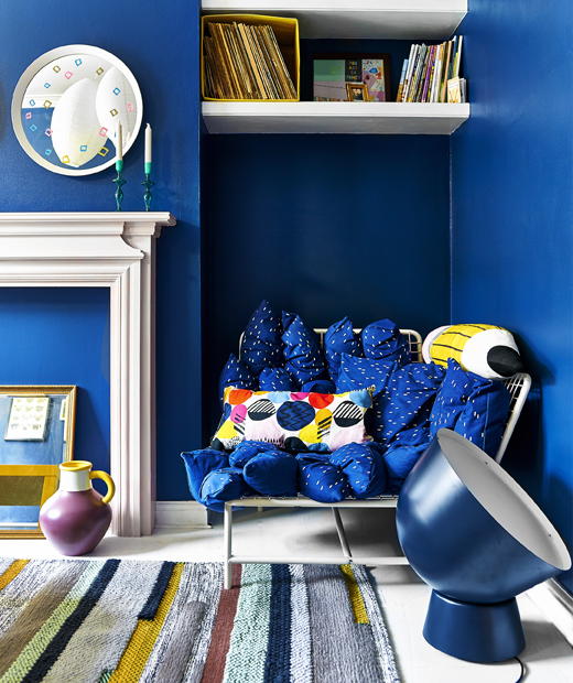 Осветена синя стая с диван, лампа и килим.